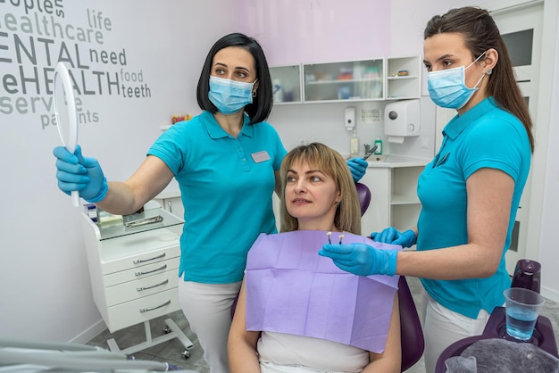 Il paziente sulla poltrona del dentista si guarda allo specchio dopo che il lavoro è terminato