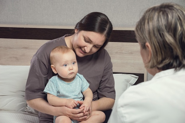 Il pediatra controlla il bambino seduto sulle ginocchia della madre