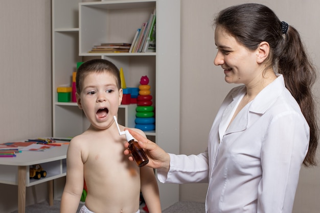 Il pediatra soffia uno spray per la gola nella bocca del ragazzo.