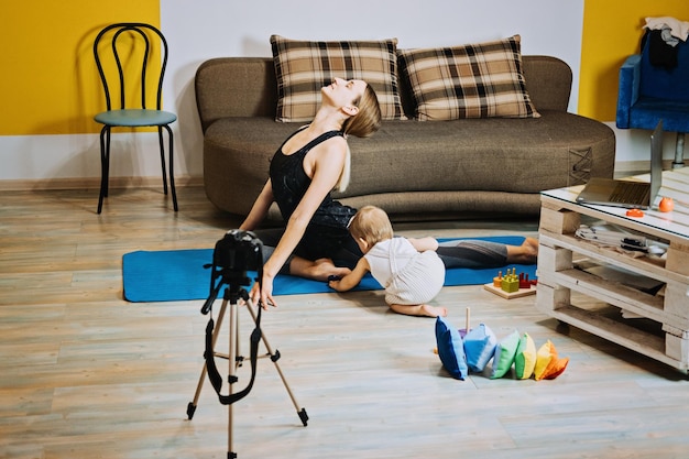 Il personal trainer dell'istruttore di fitness della madre registra il video vicino alla fotocamera a casa con la figlia