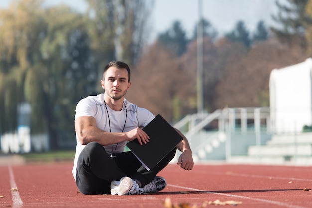 Il personal trainer in abbigliamento sportivo prende appunti sugli appunti nell'area del parco cittadino Formazione ed esercizio fisico per il concetto di stile di vita sano di resistenza all'aperto