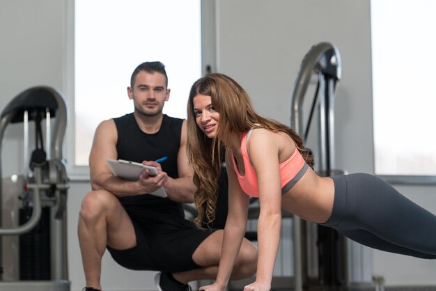 Il personal trainer prende appunti mentre la donna fa push-up