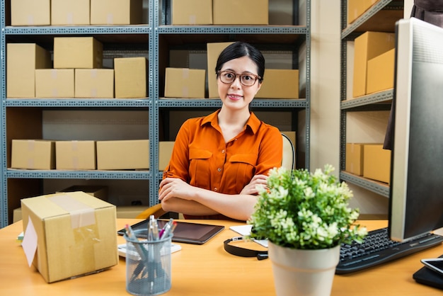 il personale dello shopping online seduto davanti alla sua scrivania è pronto per lavorare e sorridere faccia alla telecamera