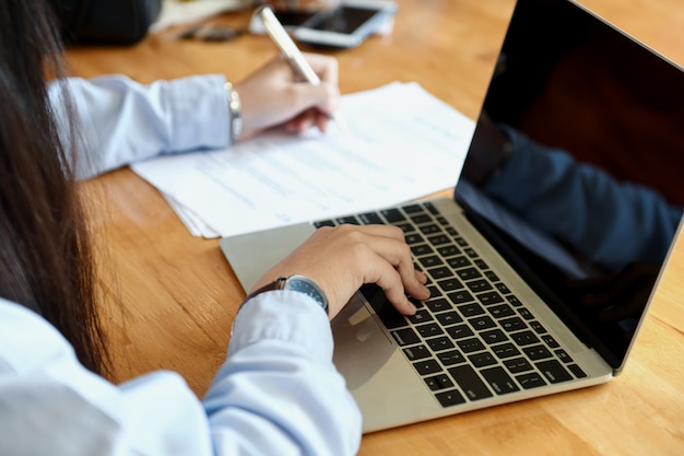 Il personale femminile dell&#39;ufficio sta prendendo le note e sta usando il computer portatile.