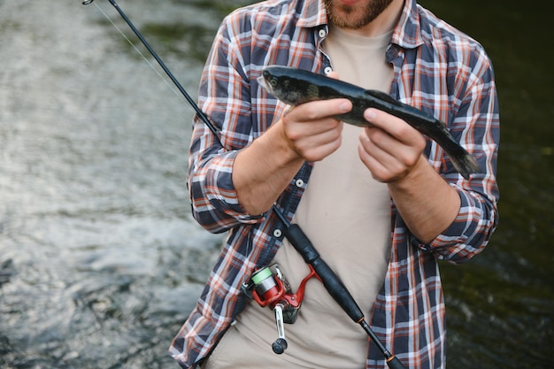 Il pescatore cattura una trota sul fiume in estate