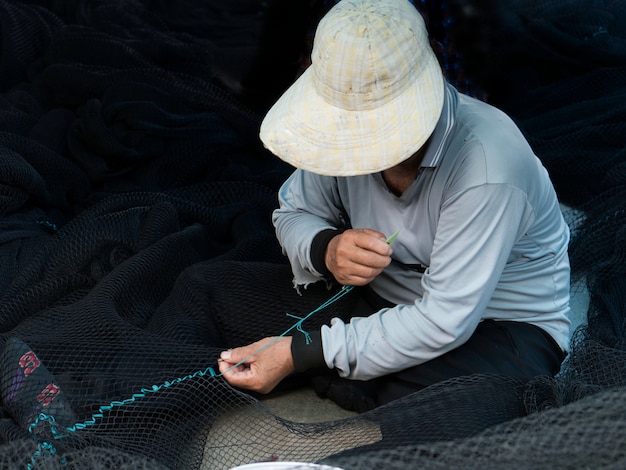 Il pescatore sta riparando le reti da pesca.