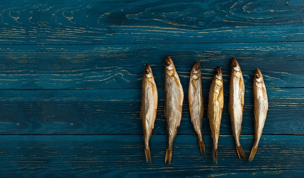 Il pesce essiccato all'odore è uno spuntino ideale per la birra. Si trova su uno sfondo di legno di tavole blu scuro.