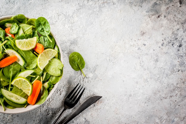 Il peso del piano di dieta perde il concetto, l'insalata della verdura fresca con la forcella, il coltello, spazio di pietra grigio della copia della tavola