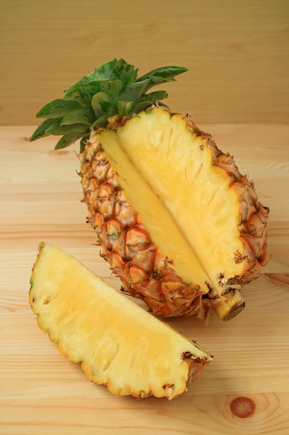 Il pezzo di ananas maturo fresco ha tagliato dall&#39;intera frutta isolata sulla tavola di legno