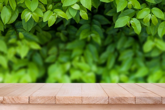 Il piano d'appoggio di legno marrone sul fondo verde astratto della natura del bokeh può essere utilizzato per il montaggio