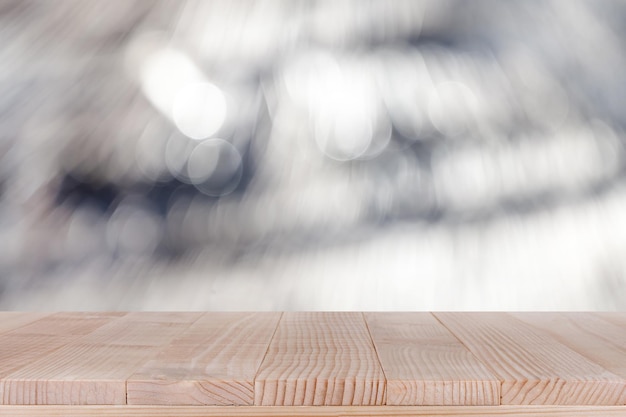 Il piano del tavolo in legno marrone su sfondo bianco astratto bokeh può essere utilizzato per il montaggio
