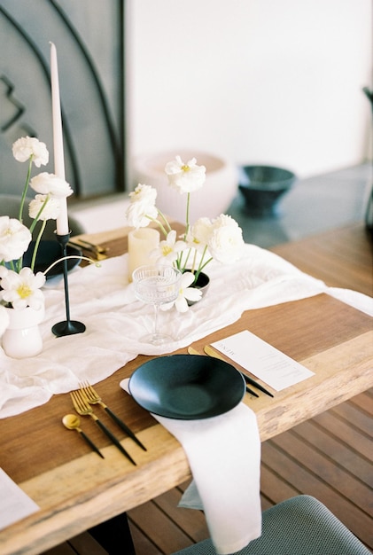 Il piatto nero si trova su un tovagliolo bianco vicino al menu e le posate dorate su un tavolo festivo