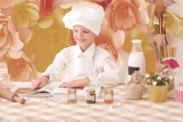 Il piccolo bambino carino sta preparando pasti gustosi in cucina