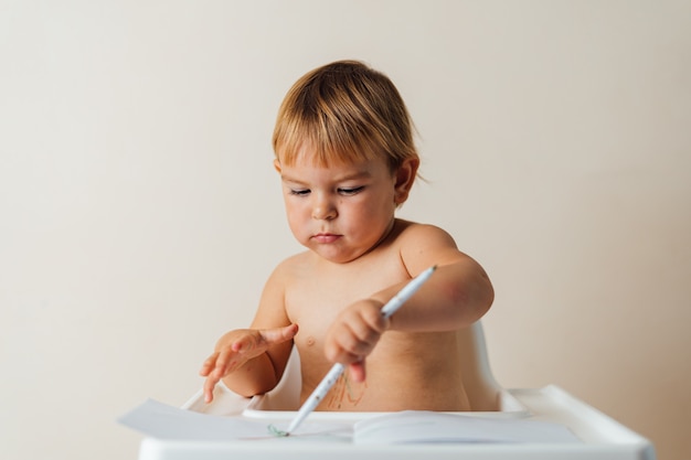 Il piccolo bambino del bambino gioca con i pennarelli, disegnando linee colorate su carta