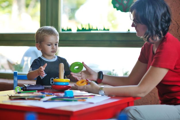 il piccolo bambino felice gioca e si diverte, lezioni di educazione nel colorato parco giochi del giardino dell'asilo al chiuso
