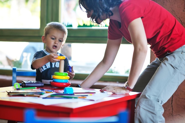 il piccolo bambino felice gioca e si diverte, lezioni di educazione nel colorato parco giochi del giardino dell'asilo al chiuso