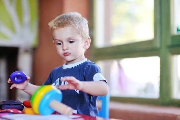 il piccolo bambino felice gioca e si diverte, lezioni di educazione nel colorato parco giochi del giardino dell'asilo al chiuso