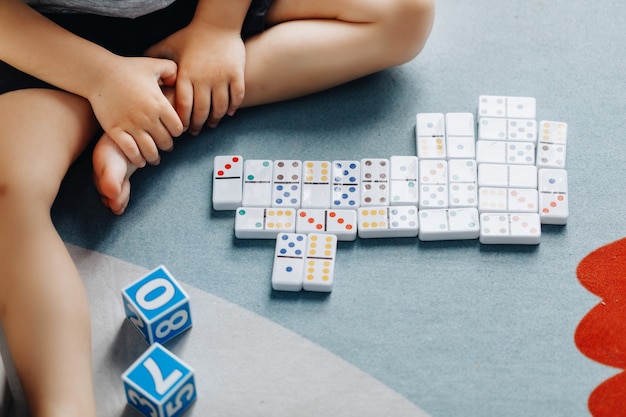 Il piccolo bambino gioca a domino nella sua stanza sul pavimento