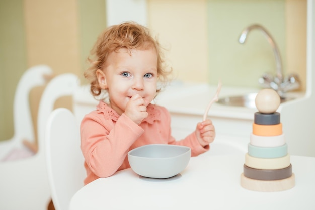 Il piccolo bambino mangia la pasta nella cucina dei bambini