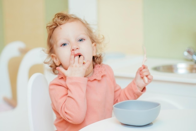 Il piccolo bambino mangia la pasta nella cucina dei bambini