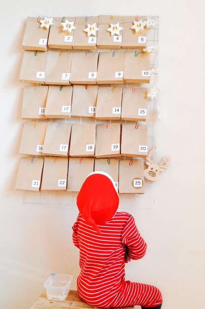 il piccolo bambino sta aspettando sullo sgabello l'inizio del calendario dell'avvento per Natale.