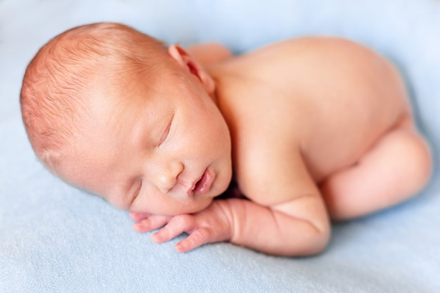 Il piccolo bambino sta dormendo su una coperta blu