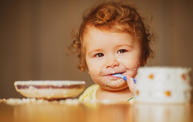 Il piccolo bambino sveglio viene nutrito usando un cucchiaio piccolo bambino che mangia purea di frutta all'interno