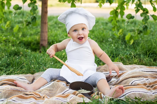 Il piccolo chef cucina e mangia la pasta in un pic-nic all'aperto