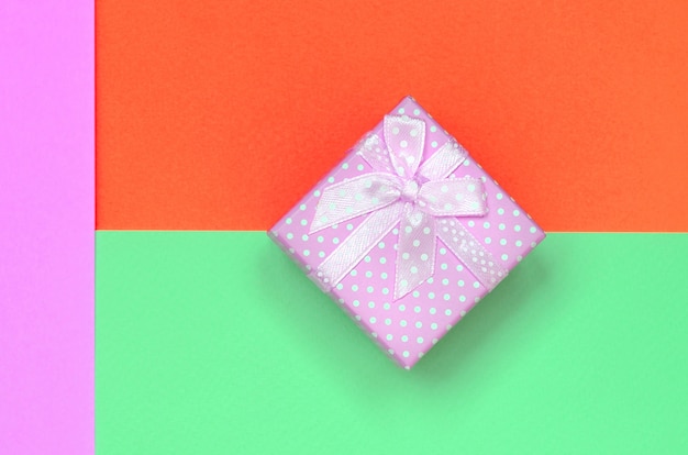 Il piccolo contenitore di regalo rosa si trova su carta variopinta