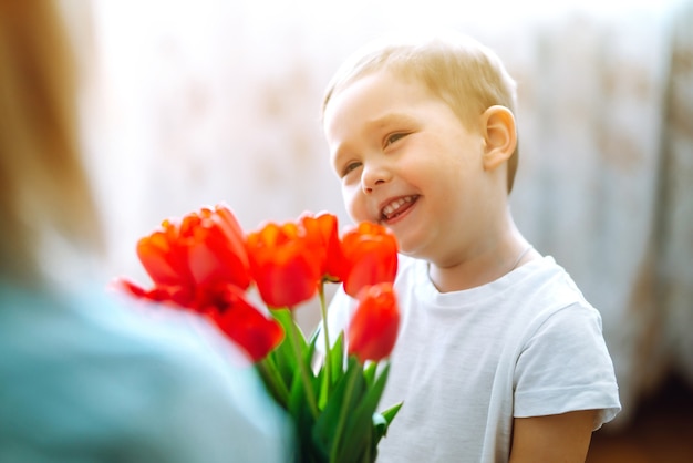 Il piccolo figlio si congratula con la madre e regala un mazzo di tulipani di fiori. Buona festa della mamma.