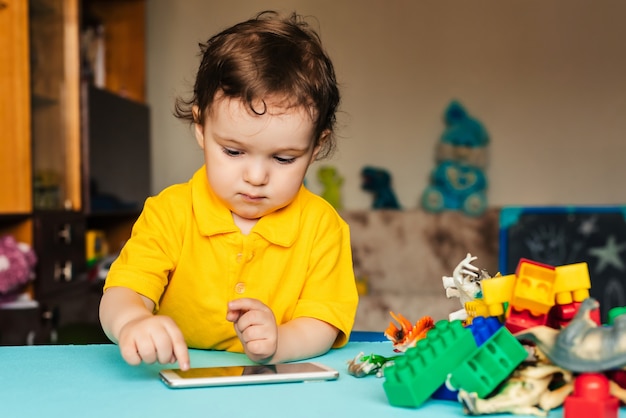 Il piccolo neonato caucasico utilizza lo smartphone a casa