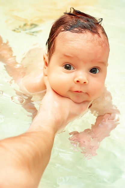 Il piccolo neonato con gli occhi grandi fa il bagno