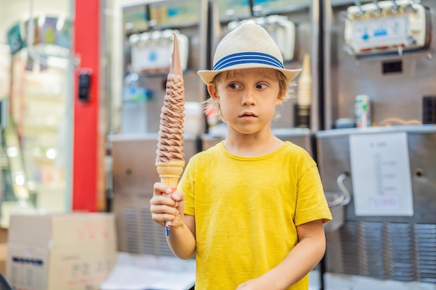 Il piccolo ragazzo turistico che mangia cm gelato lungo il gelato lungo il gelato è un turista popolare