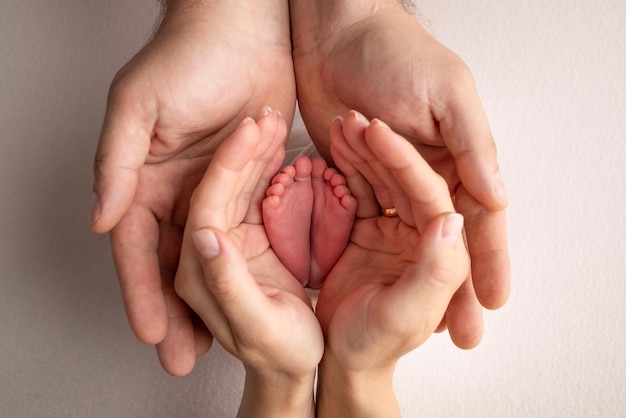 Il piede dei bambini nelle mani di madre padre genitori Piedi di un neonato piccolo primo piano Gambe di bambino Mamma e suo figlio Concetto di famiglia felice Bella immagine concettuale della maternità fotografia stock