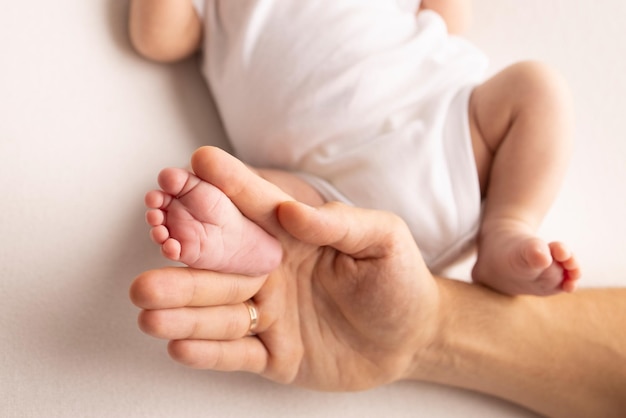 Il piede dei bambini nelle mani di madre padre genitori Piedi di un neonato piccolo primo piano Gambe di bambino Mamma e suo figlio Concetto di famiglia felice Bella immagine concettuale della maternità fotografia stock