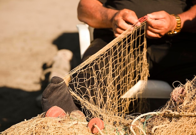 il piede del pescatore tiene la rete da pesca, l'ago rosso per la riparazione