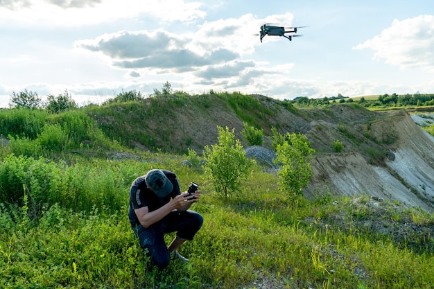 Il pilota di un veicolo aereo senza pilota tiene in mano un pannello di controllo di un drone Volare un quadricottero su una vecchia cava abbandonata Un blogger lancia un drone mentre è in viaggio