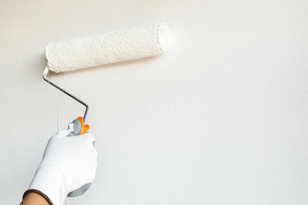 Il pittore dipinge di bianco le pareti e decora l'interno del soggiorno di casa.