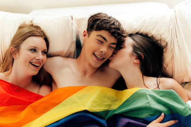 Il poliamore dei giovani si impegna in molteplici relazioni romantiche trio maschile e femminile sotto una bandiera arcobaleno