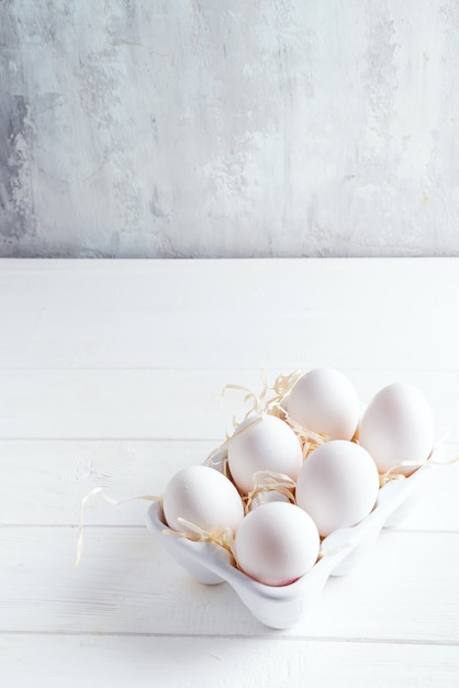Il pollo bianco organico eggs in scatola decorativa della porcellana su bianco. Cibo sano naturale e concetto organico.