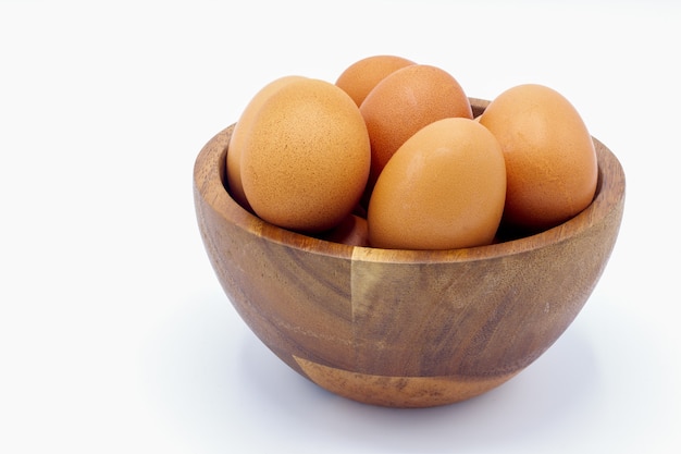 Il pollo fresco eggs in una ciotola di legno su una priorità bassa bianca