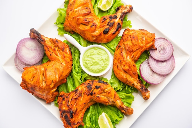 Il pollo tandoori è un piatto di pollo preparato arrostendo il pollo marinato in yogurt e spezie in un tandoor o in un forno di argilla, servito con cipolla e chutney verde