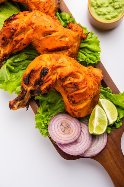 Il pollo tandoori è un piatto di pollo preparato arrostendo il pollo marinato in yogurt e spezie in un tandoor o in un forno di argilla, servito con cipolla e chutney verde