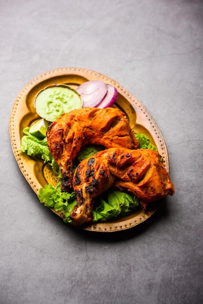 Il pollo tandoori è un piatto di pollo preparato arrostendo il pollo marinato in yogurt e spezie in un tandoor o in un forno di argilla, servito con cipolla e chutney verde