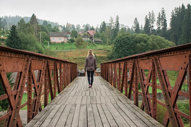 Il ponte in montagna. Ragazza che cammina su un ponte in montagna.