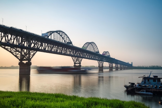 Il ponte sul fiume jiujiang yangtze al tramonto una nave portacontainer a vela motion blurxA