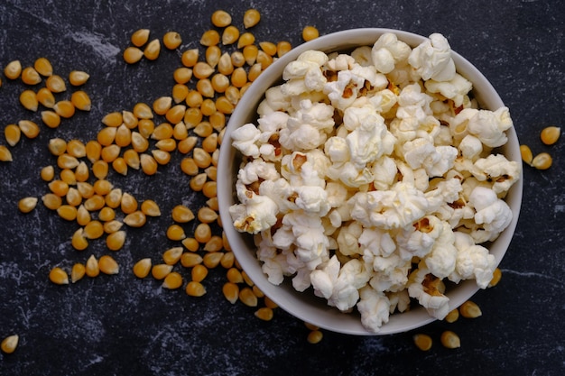 Il popcorn è una varietà di chicchi di mais che si espande e si gonfia quando viene riscaldato. Popcorn in una ciotola bianca.