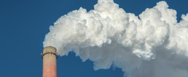 Il potente camino di una fabbrica industriale sta fumando ed emettendo anidride carbonica nell'ambiente Concetto di inquinamento atmosferico e problema del riscaldamento globale