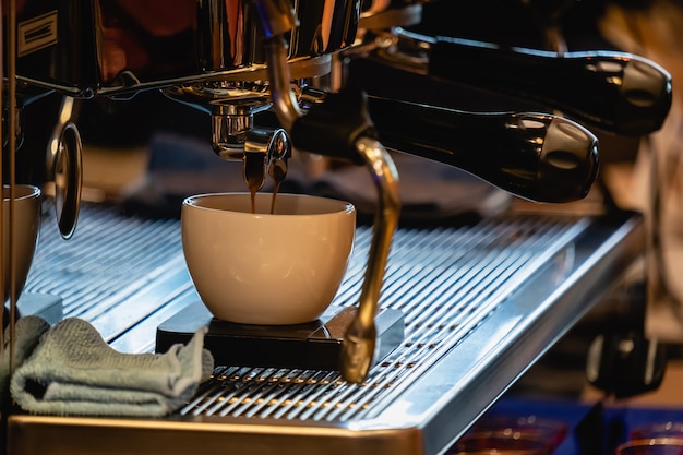 Il primo piano del caffè espresso ha sparato versando dalla macchina del caffè in caffetteria