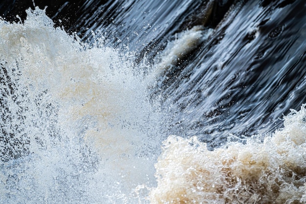 Il primo piano dell'acqua che scorre rapidamente spruzza l'acqua di un fiume di acqua bianca o di un flusso d'acqua frizzante